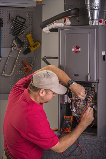 Rheem HVAC technician checking wires in furnace
